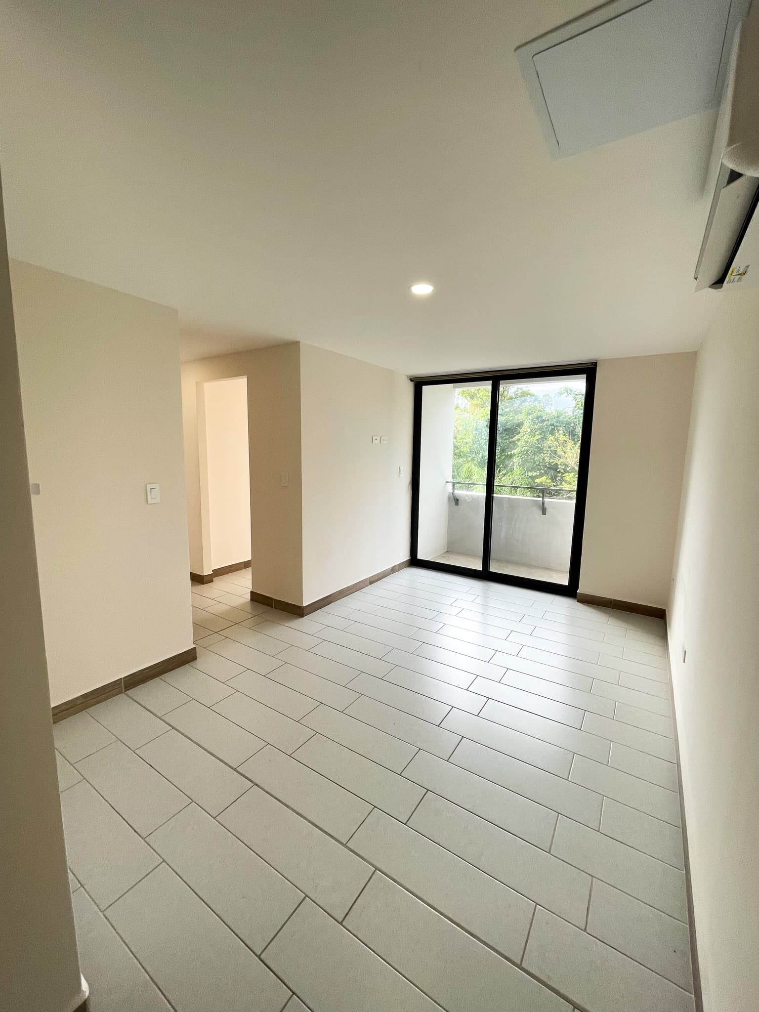 Sala amplia con balcón y vista al área verde del conjunto