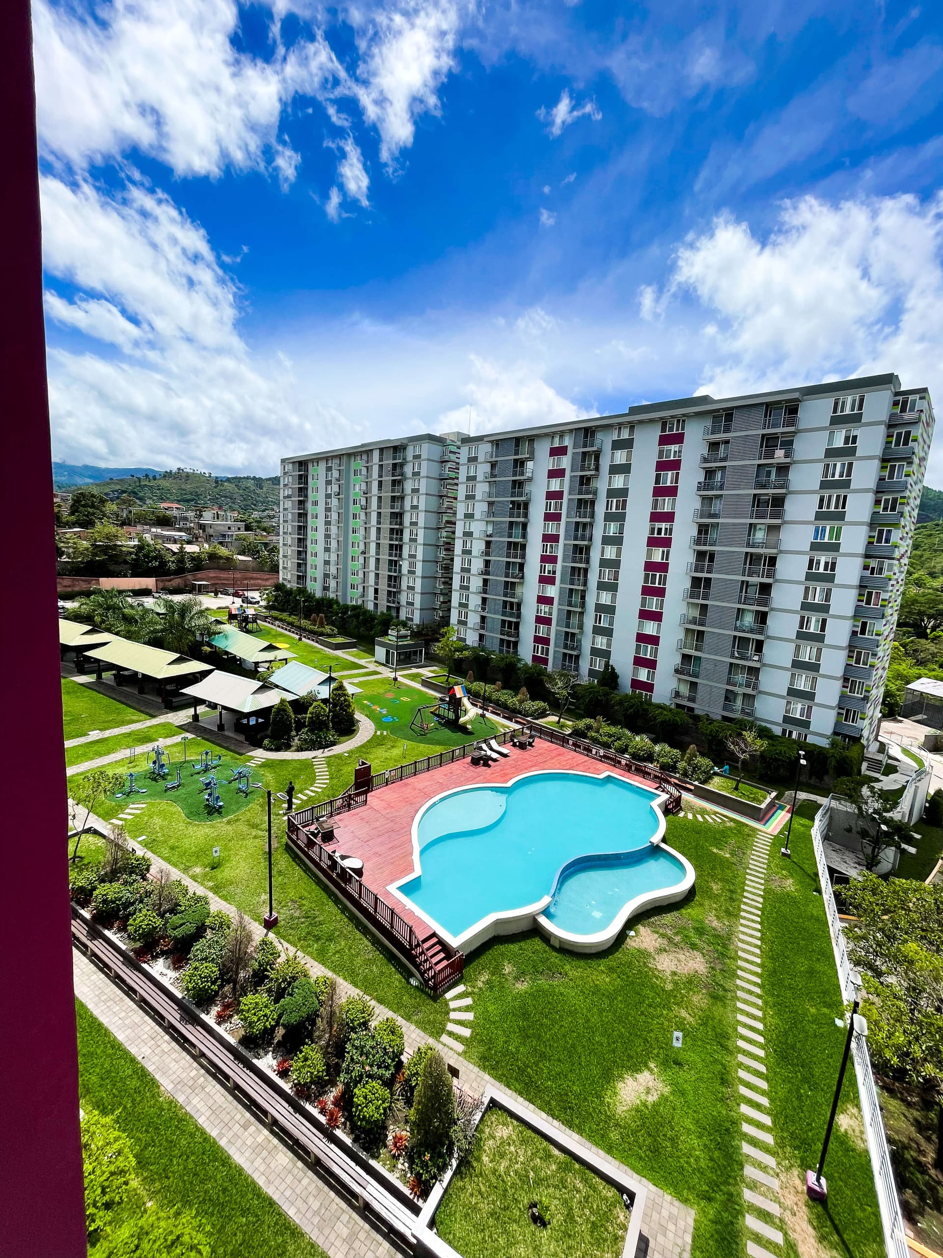 Balcón con vista a la piscina y áreas verdes del conjunto