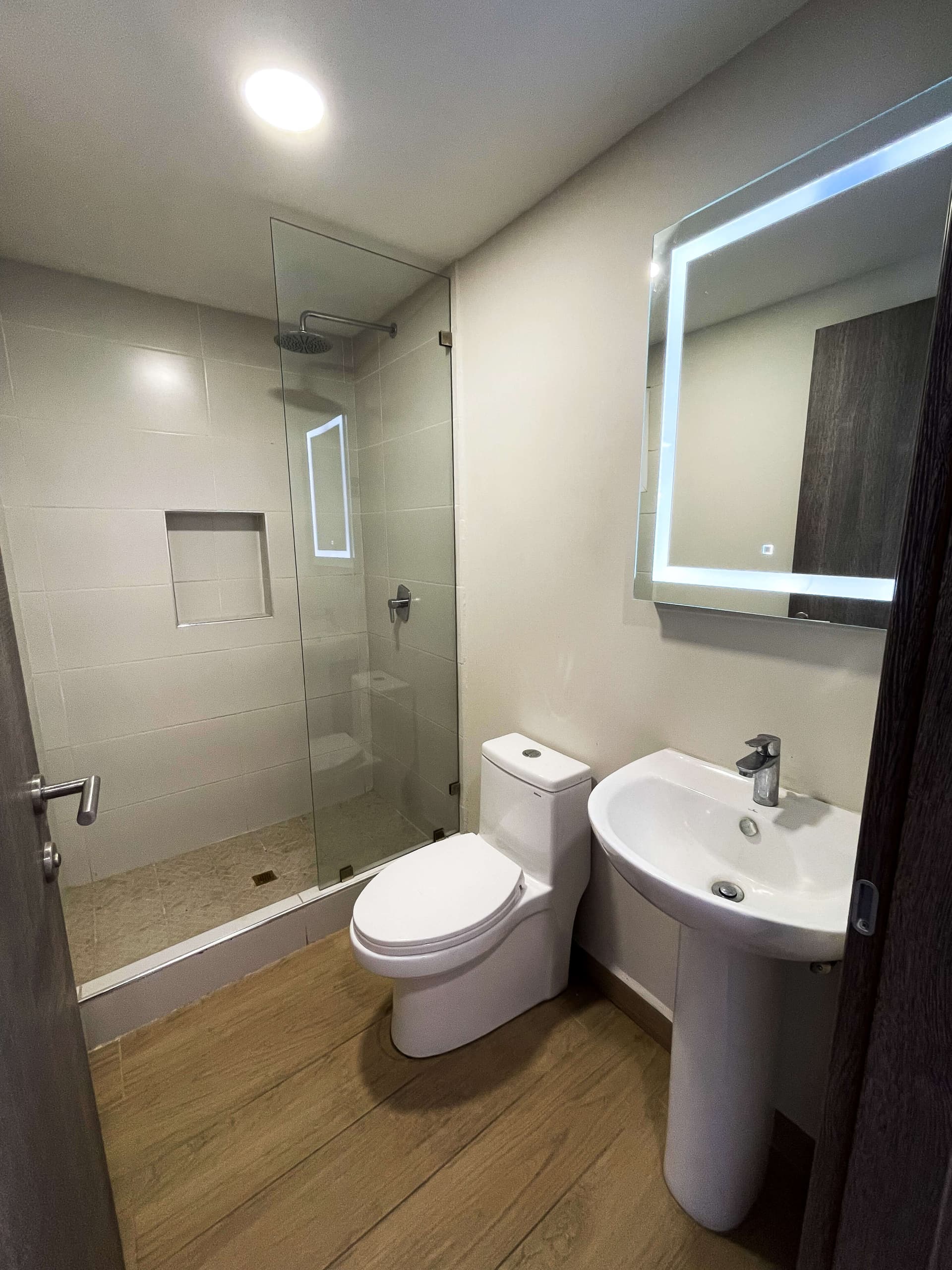 Segundo baño con ducha, inodoro y lavamanos con espejo iluminado